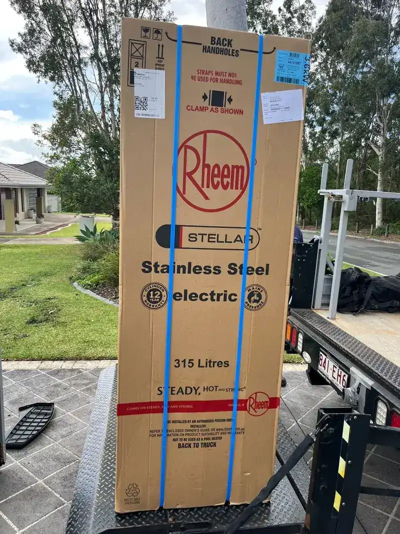A boxed Rheem Stellar 315 litre stainless steel electric hot water system on a truck tailgate at a job site