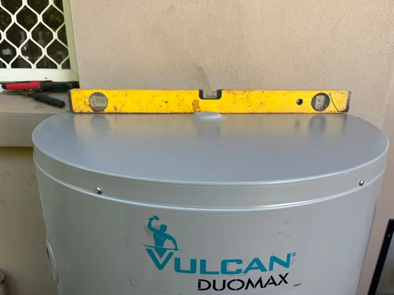 A spirit level sitting on top of a Vulcan Duomax hot water tank, checked dead level during installation