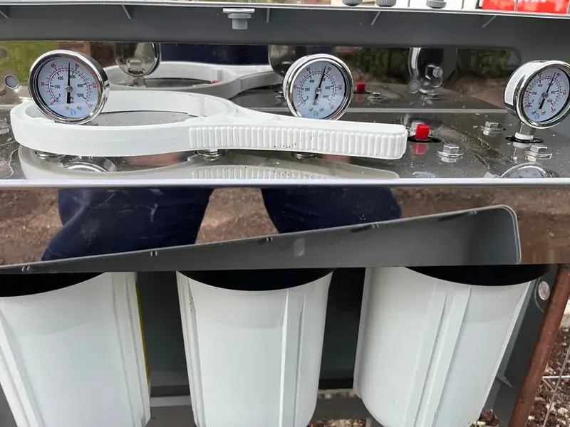 A three stage water filtration system with pressure gauges mounted above each filter housing
